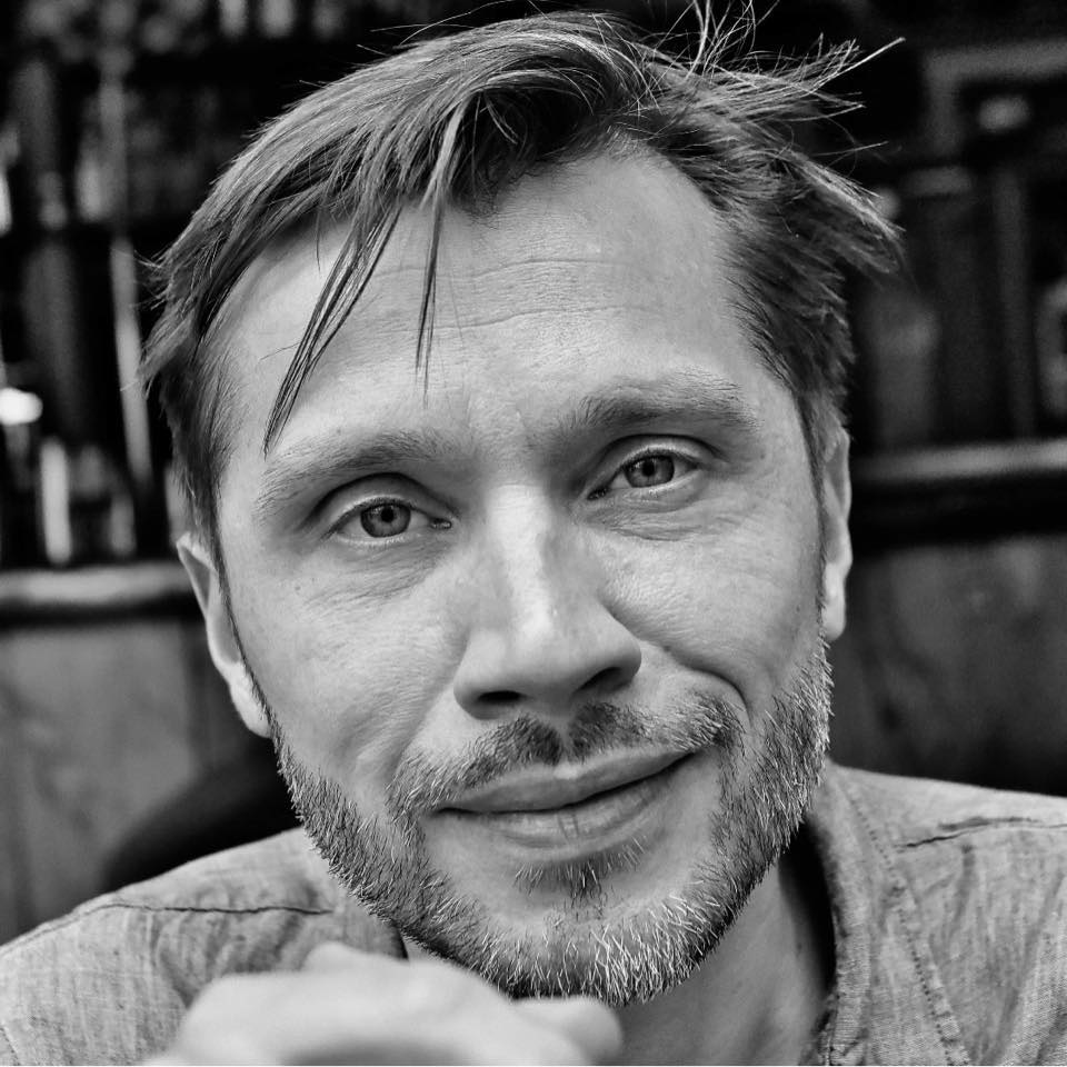 Sort-hvidt portræt af Caspar Schjelbred, der ser direkte ind i kameraet med et roligt og opmærksomt udtryk.